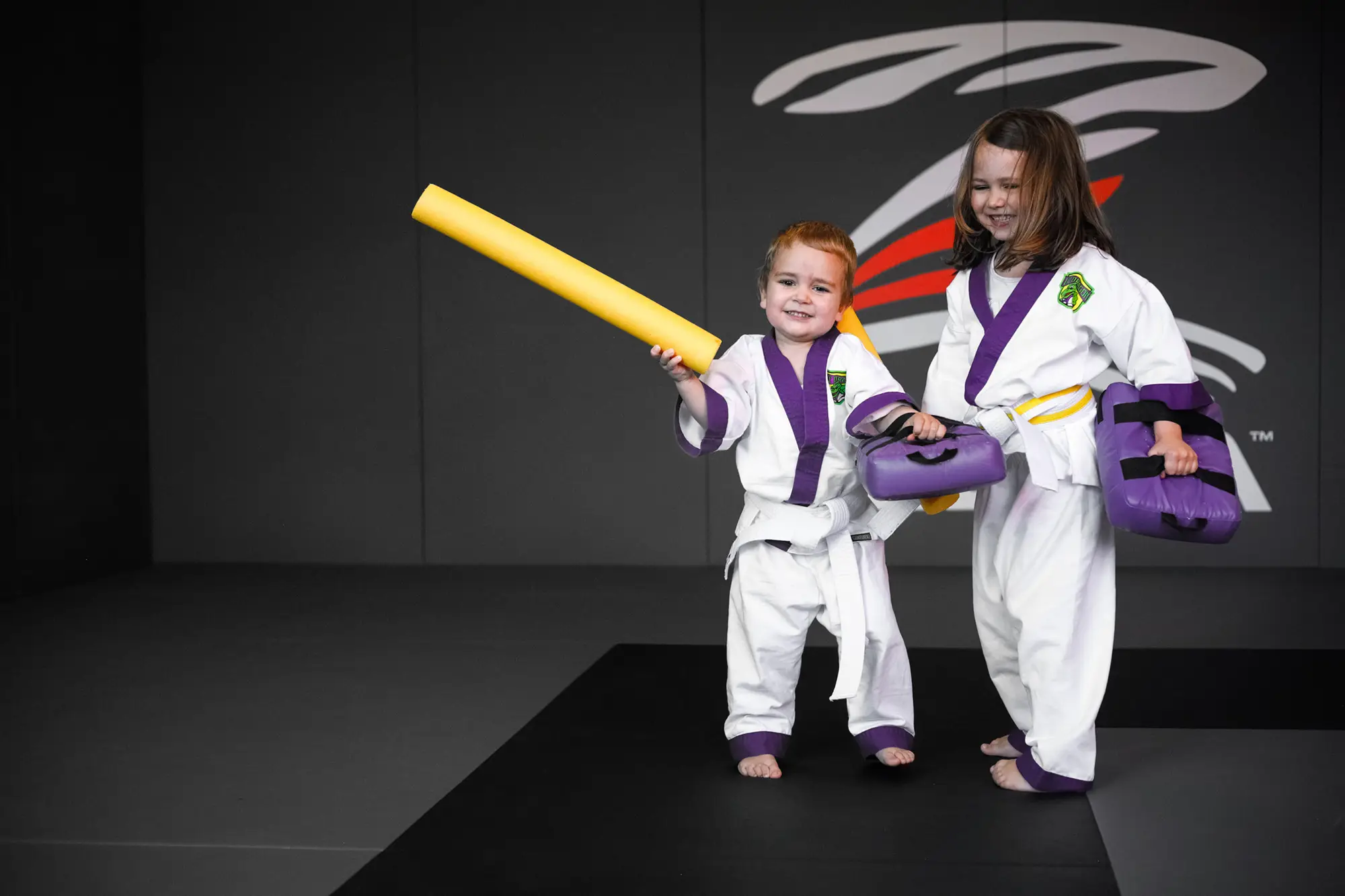 Zwei kleine Kinder im Lil' Dragon Gi mit Trainingsgeräten